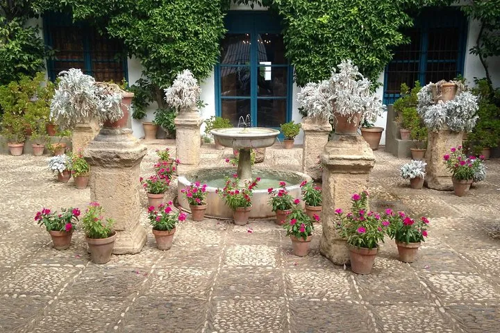Stone pedestals and terracotta pots of geraniums around a small fountain